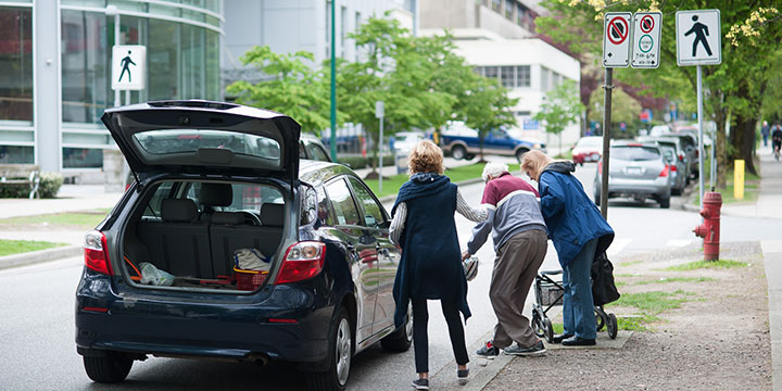 Elderly man gets helped into vehicle at a loading zone Elderly man gets helped into vehicle at a loading zone