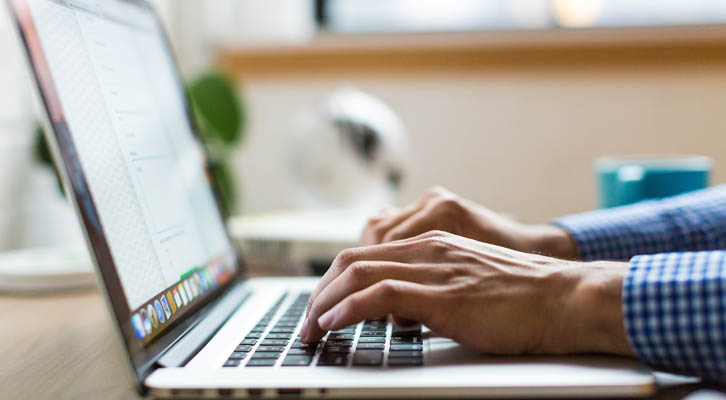 Hands typing on laptop computer keyboard