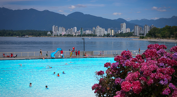 People swimming in Kits Pool with ocean and downtown in the background
