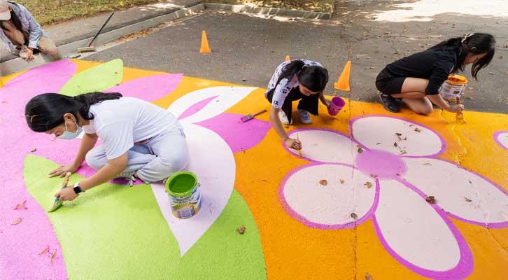 People painting a mural on pavement