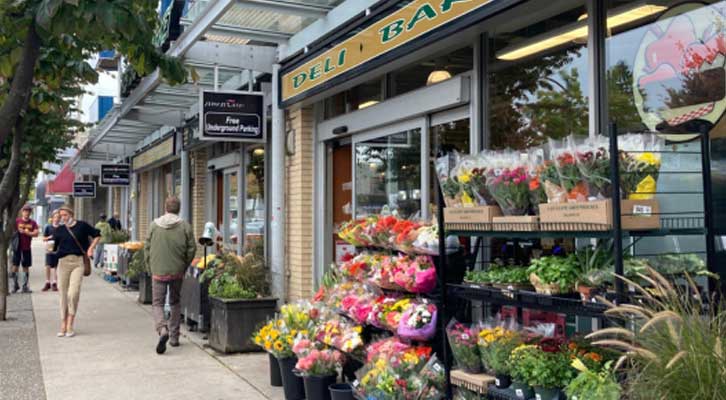 People walking down a busy street in front of a convenience store
