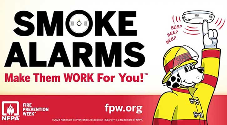 Smoke alarms make them work for you! Greyhound in firefighter uniform pushing the button on a home smoke alarm.