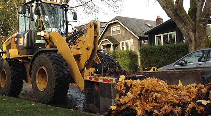 Tractor pushing leaves on a street