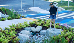 Child looking a drainage pipe in park-like setting