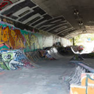 A tunnel in a skatepark with graffiti and obstacles