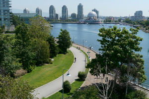 Person riding bike along pathway along False Creek