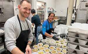 Three people preparing meals in a commercial kitchen.