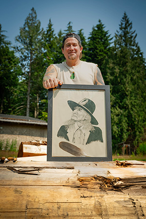 Zac George holding a portrait of the late Chief Dan George