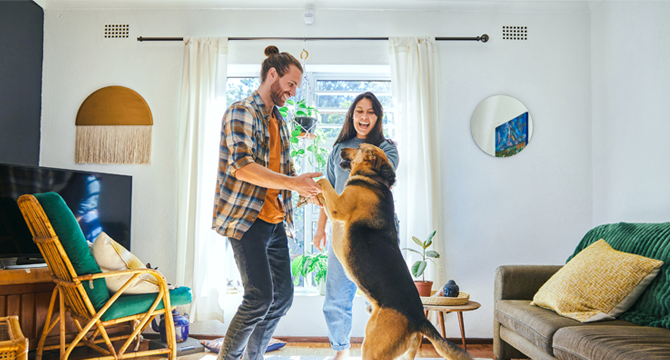 Two people dancing with their dog in the living room