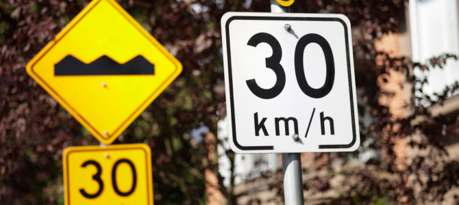 Signs displaying the speed limit of 30kph and a speed bump sign Signs displaying the speed limit of 30kph and a speed bump sign
