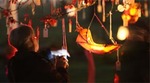 Woman looking at lanterns hanging from a tree Woman looking at lanterns hanging from a tree