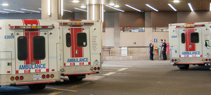 Three ambulances parked at VGH Emergency with paramedics in the background