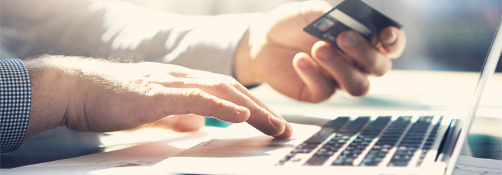 Man holding bank card while on laptop