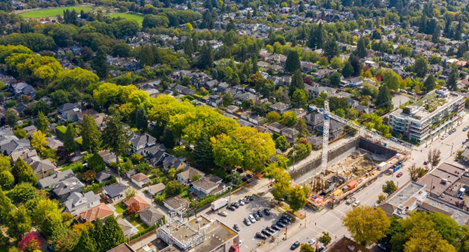 Aerial view of a neighbourhood surrounded by trees and a construction site