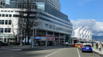 Canada Place and street with pedestrians, cars, and mountains in the background.