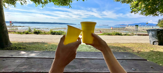 Two people with cups in front of a beach