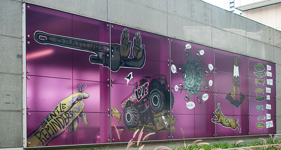A magenta mural titled Gentle Reminders by Cheryl Hamilton, featuring surreal images including a wrench with flowers, a monster truck, and a hand. A magenta mural titled Gentle Reminders by Cheryl Hamilton, featuring surreal images including a wrench with flowers, a monster truck, and a hand.