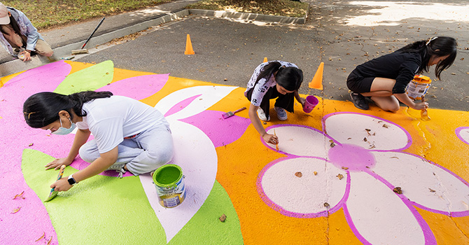 Children painting a colourful ground mural with flowers Children painting a colourful ground mural with flowers