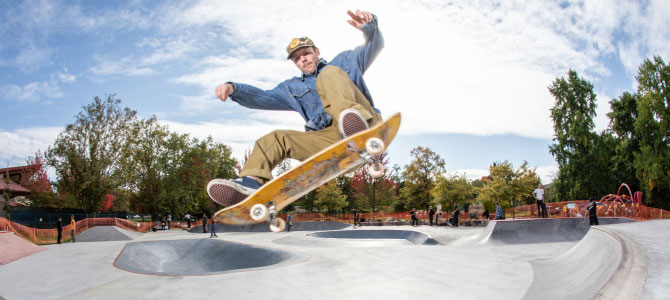 A skateboarder mid-air performing a trick at an outdoor skatepark.