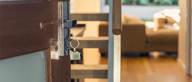 The front door of a home with a key in the lock The front door of a home with a key in the lock