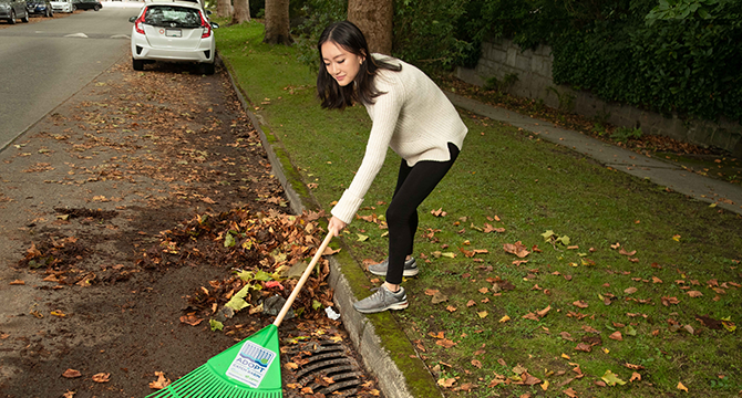 Woman clearing a catch basin with a rake