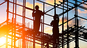 Construction workers on a scaffold at sunrise