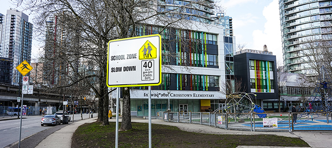 	 A school zone slow down 40 km/h sign in the foreground of Crosstown Elementary.