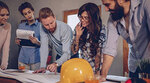 5 people standing around a table looking at building blueprints