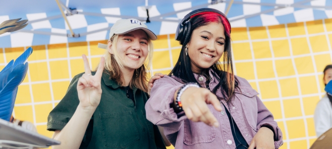 Two people DJ in a tent outdoors