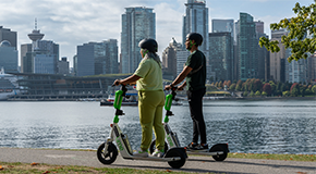 Two people ride escooters on the seawall