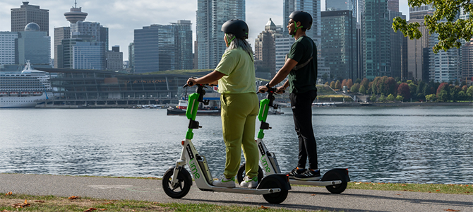 Two people ride escooters on the seawall