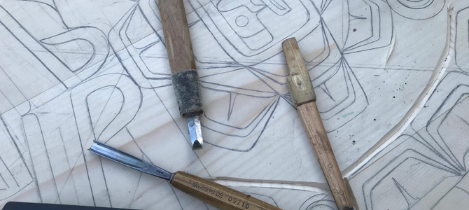 Wood carving tools on top of a piece of an artist's sketch