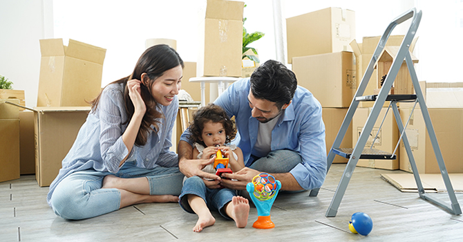 A family sitting on a floor with moving in equipment 