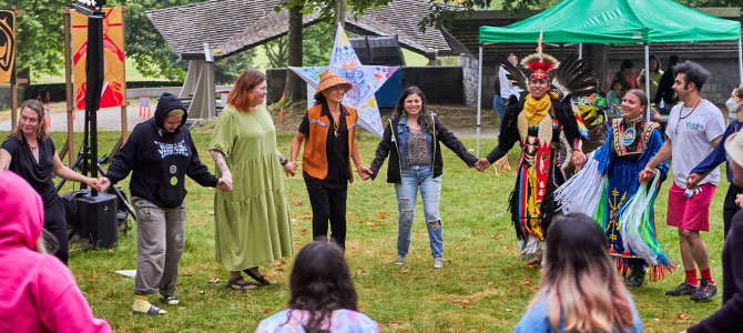 group of people holding hands and dancing in a circle