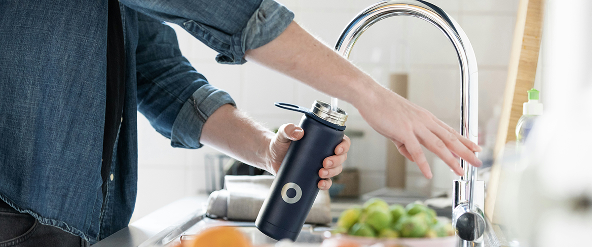 Person filling a black bottle with water from a tap