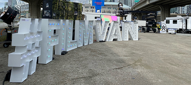 An installation of large white block letters reading #FilmVan in front of a downtown Vancouver filming location