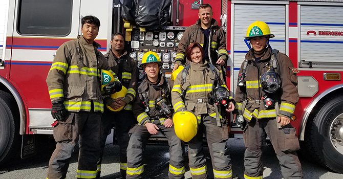 Firefighters pose for a group photo in front of a fire truck.