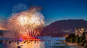 Fireworks exploding into red and white colours over Vancouver's English Bay beach during the Celebration of Light festival