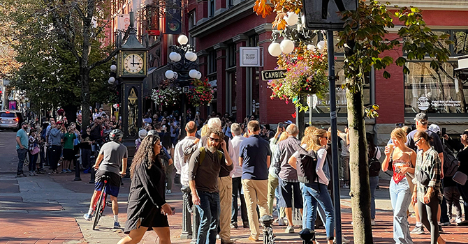 Pedestrians and cyclists on Water St near the steam clock. 