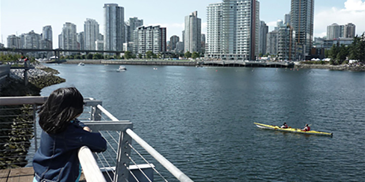 Young girl watching people kayaking on False Creek