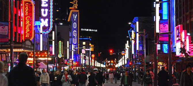 People walking along downtown Granville Street at night.