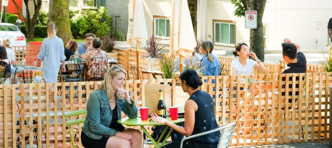 A group of people sit at a street patio