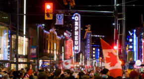 People on Granville Street at night holding Canadian flags