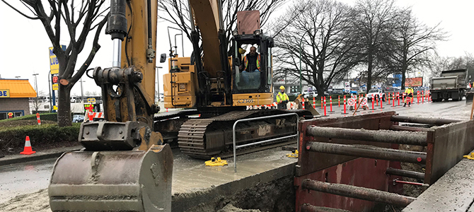 Excavator digging up sewer line with opening visible