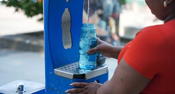 Woman at a fountain pouring water into a water bottle