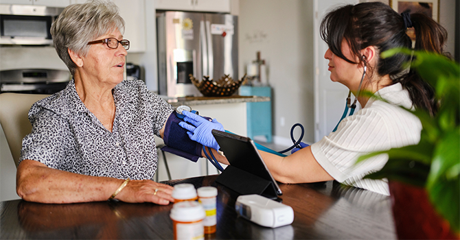 Healthcare worker taking blood pressure from a patient at home. 