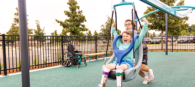 A child beams with joy while being pushed by an adult on a swing