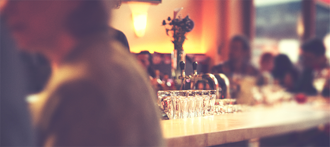 Liquor shots sit on a bar in a restaurant with people around Liquor shots sit on a bar in a restaurant with people around
