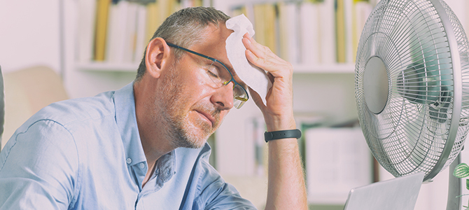 Man suffering from heat sitting in front of a fan