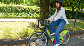 Person riding a Mobi by Rogers e-bike with helmet on a sunny day